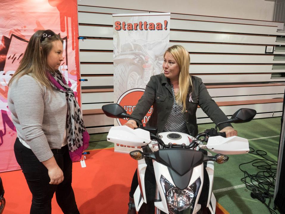 Autokoulu Epicin Katariina neuvoo Kaisa Terhosaloa ajokoulutuksessa käytettävään moottoripyörään tutustumisessa.