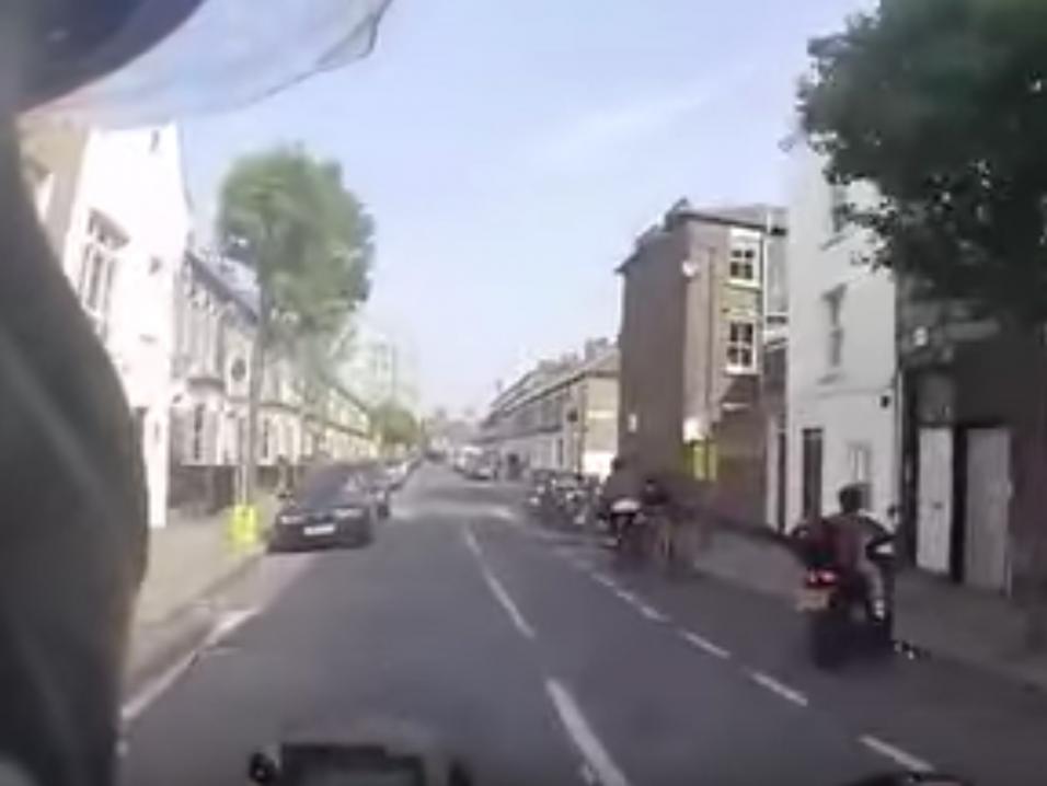 Mies ajaa BMW-moottoripyörällään takaa skootterivarasta.