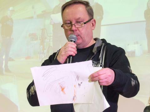 Jari Kielisen kädessä lasten piirrustuskilpailussa kunniamaininnan saanut piirrustus 'Mopo, joka kiertaa Päitsiä, jonka oli piirtänyt Vivian 2v. 