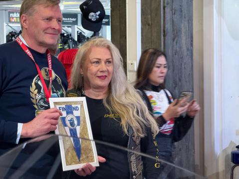 Gold Wing Club Finland -kerhon puheenjohtaja Anne Lahdenne ojensi Markku Hämäläiselle kerhon viirin tilaisuuden kunniaksi.