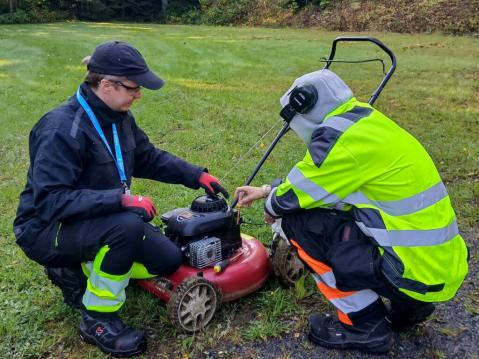 Opetuksen ohjaaja Harri Harimaa opastaa opiskelijaa tarkistamaan ruohonleikkurista öljyt.