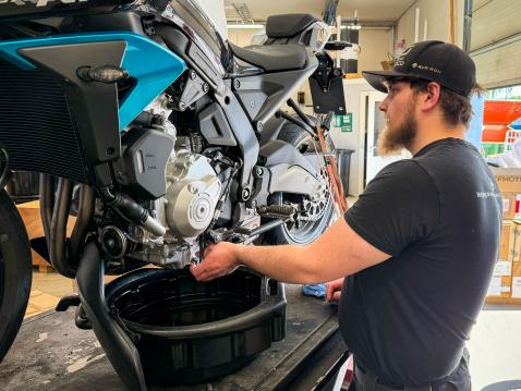 Maahantuojan eli Top Motorin mp-asentaja Eetu aloittamassa öljynvaihtoa.