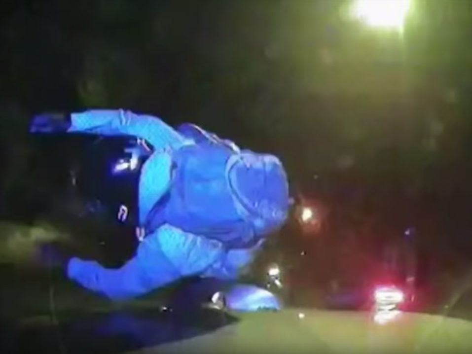 Skootterikuljettaja kaatumassa sen jälkeen, kun poliisiauto on tarkoituksella törmännyt skootteriin pysäyttääkseen varkaan.