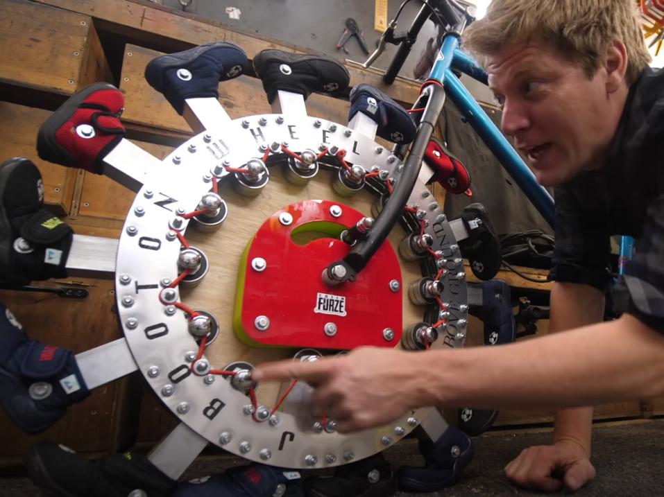 Colin Furze selostamassa kävelevän, jaloilla varustetun pyörän toimintaa.