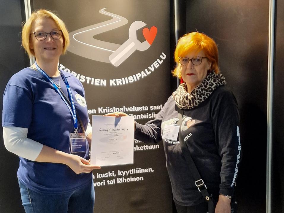 Kiitosmaininnan Motoristien Kriisipalvelun auttamisesta sai Touring Finlandia. Kunniakirjaa ojentamassa Marja Suominen (kuvassa oikealla). Kuva Motoristien Kriisipalvelun arkisto.