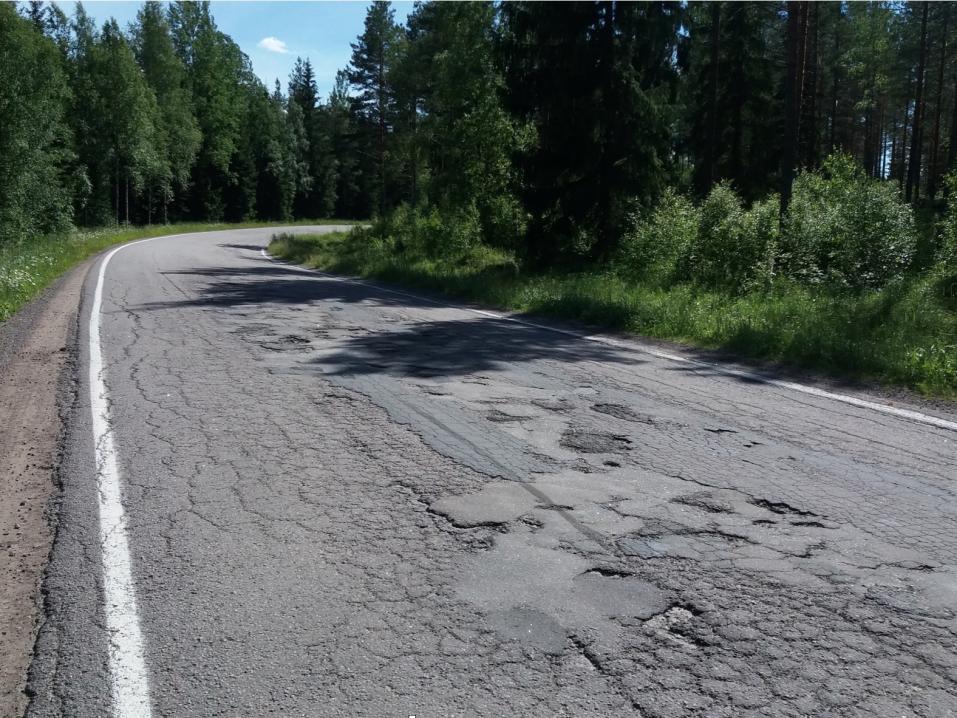 <p>Kuva 1. Kuvattu suunnasta Yläne suuntaan Mynämäki eli moottoripyöräilijä tuli kaarteesta kuvaajan suuntaan. Asfaltti huononee kaarteessa, varjoja kuoppien kohdalla.</p>